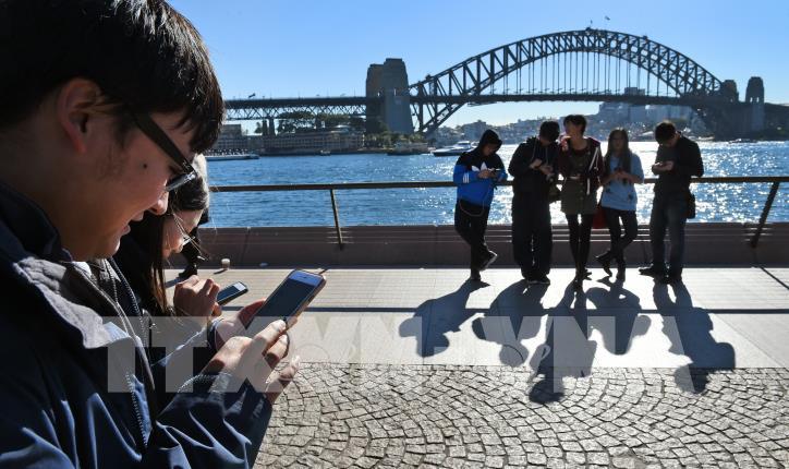 Người dân dùng điện thoại để truy cập Internet tại Sydney, Australia. (Ảnh: AFP/TTXVN) Người dân dùng điện thoại để truy cập Internet tại Sydney, Australia. (Ảnh: AFP/TTXVN)